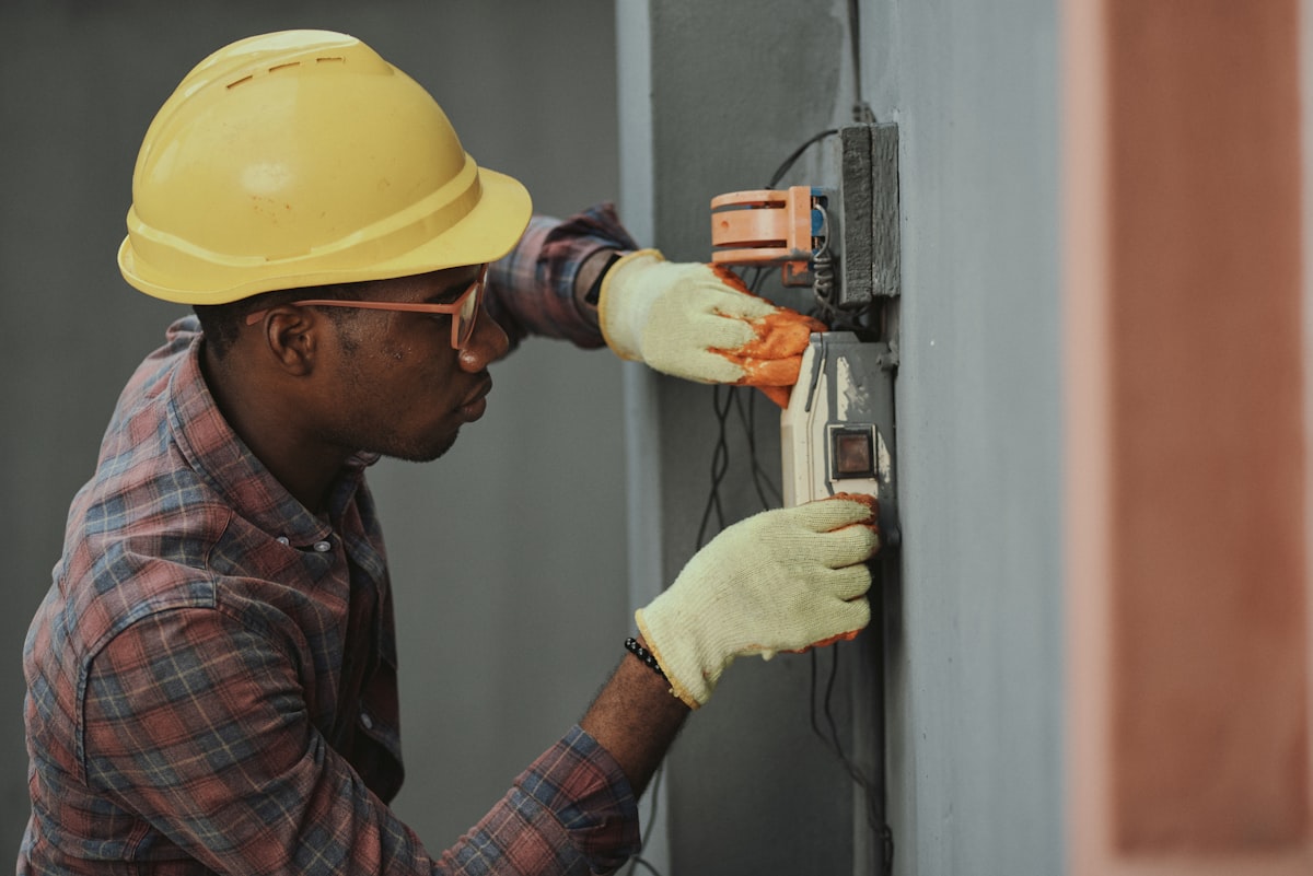 Un électricien concentré sur une installation, pendant que Constar répond à ses appels
